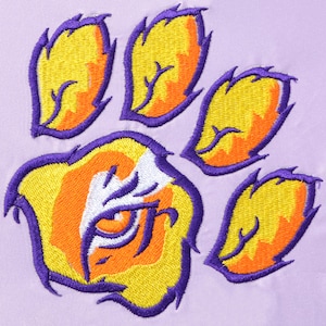 Op de afbeelding: Paarse geborduurde pootprint met een oranje en gele tijgeroog in het midden.