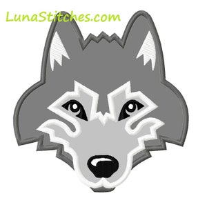 May include: A grey wolf's head with white accents and black eyes. The wolf's mouth is closed and its nose is black.