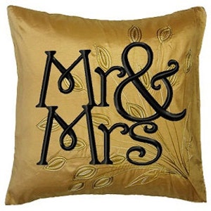 May include: Gold velvet pillow with black embroidery of "Mr & Mrs" with a leafy design.