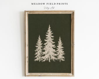 May include: A framed wall art print featuring a dark olive green background with a light beige illustration of three pine trees. The frame is made of light-toned wood with a weathered texture. The text MEADOW FIELD PRINTS Vintage Art is visible.