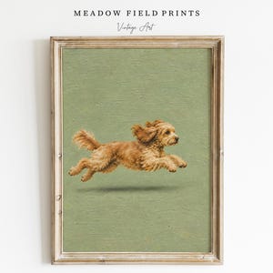 Peut inclure: Une impression d'art encadrée représentant un chien brun doré en plein saut, dans une pose de course sur un fond vert sauge uni. Le texte MEADOW FIELD PRINTS et Vintage Art est imprimé en noir au-dessus du cadre en bois.