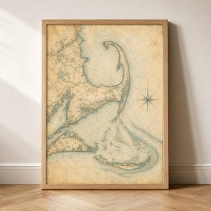 Peut inclure: Une carte marine encadrée de Cape Cod, Massachusetts, imprimée sur du papier vieilli couleur parchemin. La carte présente des contours côtiers détaillés, des sondages de profondeur et une rose des vents dans des tons bleu et beige.