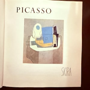 Op de afbeelding: Een boekpagina met de tekst PICASSO bovenaan en SKIRA onderaan. In het midden staat een reproductie van een kubistisch schilderij met een gitaar en een fles in tinten blauw, geel, wit en bruin op een lichtgrijze achtergrond.