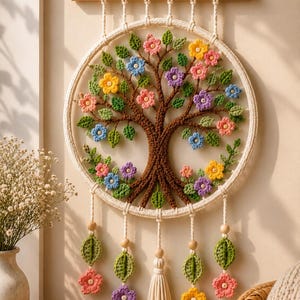 May include: A circular macrame wall hanging featuring a brown crocheted tree with green leaves and multi-colored flowers in pink, yellow, blue, and purple. The design is suspended from a wooden dowel and includes hanging cords with beads and tassels.