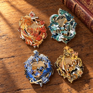 May include: Four decorative enamel pins featuring intricate designs of animals and flowers. The top left pin shows a lion with roses in orange and red. The top right pin features a snake with lilies in teal. The bottom left pin displays a bird with blue flowers. The bottom right pin depicts a badger with yellow sunflowers.