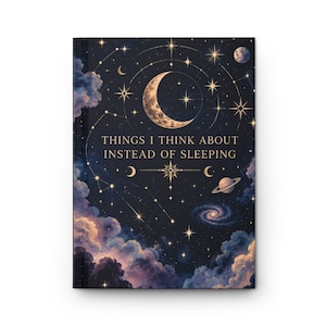Könnte beinhalten: Ein Notizbuch mit festem Einband und einem dunkelblauen Nachthimmel-Motiv, das einen Halbmond, Sterne, Planeten und Wolken zeigt. Der Text "THINGS I THINK ABOUT INSTEAD OF SLEEPING" ist in goldener Schrift in der Mitte des Designs gedruckt.