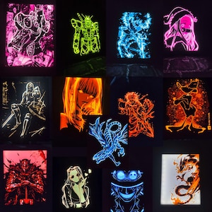 May include: A collection of rectangular LED light panels featuring various anime and cartoon character illustrations in vibrant neon colors including pink, green, blue, orange, and red against dark backgrounds, creating a glowing effect.