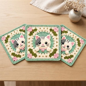 May include: Three square crochet coasters featuring a central circular motif with a white and gray cat face, pink collar, and bell. The border is cream-colored with green leaves and small pink flowers, finished with a light green scalloped edge.