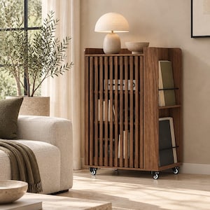 May include: A dark wood storage cabinet featuring a slatted front door, internal shelving, and side storage compartments with black metal bars. The rectangular unit is supported by four small black wheels and holds a beige lamp and a small bowl on top.