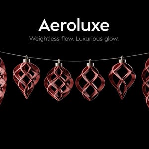 Könnte beinhalten: Sechs dunkelrote, durchbrochene, geometrische Ornamente hängen an einer dünnen Schnur vor schwarzem Hintergrund. Der Text Aeroluxe und Weightless flow. Luxurious glow. steht über den Ornamenten, die komplexe, spiralförmige, käfigartige Designs aufweisen.