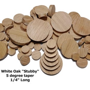 May include: A collection of light brown, round wooden pieces, varying in size, with visible wood grain. The text "White Oak 'Stubby' 5 degree taper 1/4" Long" is printed at the bottom. These wooden pieces are likely for crafting or woodworking projects.