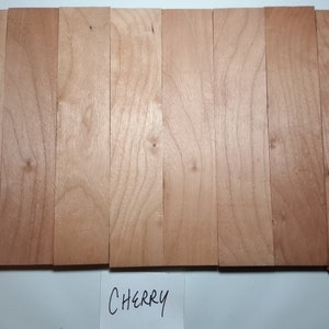 May include: Eight pieces of cherry wood, each approximately 1/2 inch wide and 12 inches long. The wood is a light brown color with a natural grain pattern. The wood is labeled "CHERRY".