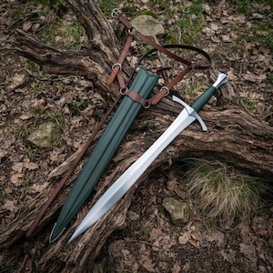 May include: A steel sword with a dark green grip and a matching dark green scabbard. The scabbard is attached to a brown leather harness with metal buckles and rings. The sword features a silver crossguard and a pointed, double-edged blade.
