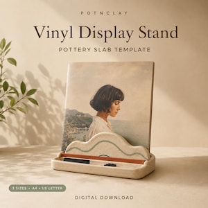 May include: A beige ceramic vinyl display stand featuring a wavy top edge with a thin green line and a terracotta-colored base. The stand holds a square record sleeve depicting a person in profile. Text reads: POTNCLAY Vinyl Display Stand.