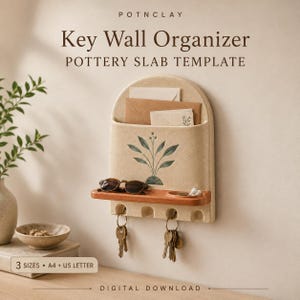 Pode incluir: Um organizador de parede de cerâmica bege com topo arredondado, ilustração de folha verde, prateleira de madeira com óculos de sol e quatro ganchos com dois conjuntos de chaves. Texto: POTNCLAY Key Wall Organizer POTTERY SLAB TEMPLATE.