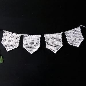 May include: White crocheted banner with the word "2016" spelled out in individual flags. The banner is decorated with small red and green holly sprigs.