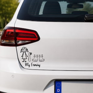 Peut inclure: Un autocollant de voiture en vinyle noir représentant un personnage en bâtonnet représentant une fille, un objet haut et deux chats, avec le texte My Family écrit en écriture cursive sous les personnages. L'autocollant est sur le coffre d'un véhicule blanc.