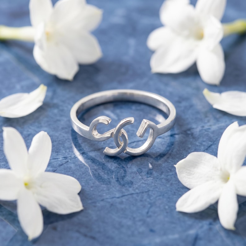 925 sterling silver custom two initial ring resting on blue stone, delicate white floral accents