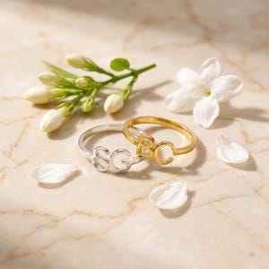 Gold and silver custom two initial rings on a marble slab with white blooms, elegant initial signet ring display