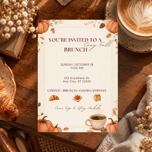 May include: A rectangular invitation card with a cream background featuring orange pumpkins, autumn leaves, and acorns. The text reads: YOU'RE INVITED TO A Cozy Fall BRUNCH, SUNDAY, OCTOBER 18, 11:00 AM, 123 Anywhere St., Any City, ST 12345, COFFEE, BRUNCH, GOOD COMPANY, Come Sip & Stay Awhile.