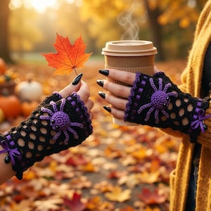 May include: A pair of black fingerless crochet gloves featuring a purple spider appliqué, purple ribbon accents, and small black beads. The gloves have a mesh-like pattern and are worn with a mustard yellow knit cardigan, holding a maple leaf.