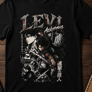 May include: A black short-sleeve t-shirt featuring a graphic print of the character Levi Ackerman from Attack on Titan. The design includes the text LEVI Ackerman, Japanese characters, and illustrations of the character in action poses with blades.
