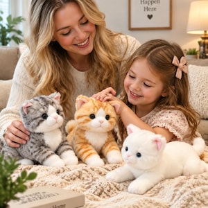 May include: Three plush cat toys in a sitting or lying position. One cat is gray and white with tabby stripes, one is orange and white with tabby stripes, and one is solid white. Each cat has pink inner ears, black eyes, and white paws.