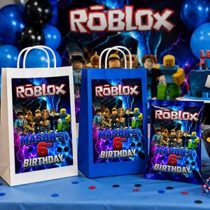Puede incluir: Dos bolsas de regalo rectangulares y una bolsa de aperitivos con temática de Roblox, gráficos de rayos azules, varias figuras de personajes y el texto Mason's 6th Birthday. Las bolsas de regalo tienen asas blancas y la bolsa de aperitivos está sellada.