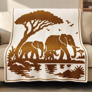 May include: A rectangular crochet blanket featuring a two-tone brown and cream pixelated design. The pattern depicts a savanna scene with a large acacia tree, a group of elephants, and birds in flight, all reflected in a body of water below.