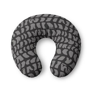 May include: A U-shaped neck pillow featuring a repeating pattern of dark grey abstract shapes on a black background. The pillow has a curved, ergonomic design intended to support the neck and head, with a consistent print across the entire surface.