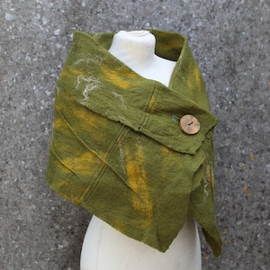 May include: A green felted shawl with yellow accents and a wooden button. The shawl is draped over a white mannequin.