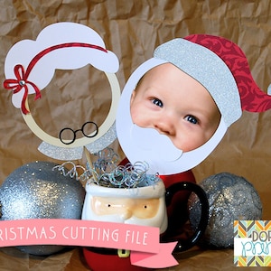 May include: A printable Christmas cutting file featuring a Santa and Mrs. Claus face cutout with a white beard and a red hat with silver glitter. The file is perfect for creating personalised Christmas decorations.