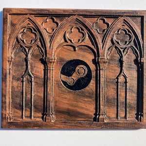 May include: A rectangular wooden wall plaque featuring a dark brown finish with carved architectural details resembling gothic arches and trefoil motifs. A circular black inlay is centred in the middle, displaying a raised Steam logo icon.