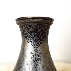 May include: A silver pitcher with intricate black floral designs etched into the surface.