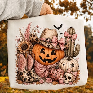 Könnte beinhalten: Eine weiße Stofftasche mit einem farbenfrohen Grafikdruck eines Kürbisses, der einen Cowboyhut mit Leopardenmuster und einer rosa Schleife trägt, sowie Cowboystiefeln, einem Kaktus mit rosa Schleife, einem Totenkopf, einer Kerze und Herbstlaub.