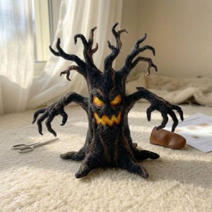 May include: A needle-felted sculpture of a dark, gnarled tree with outstretched, claw-like branches. The tree features a menacing face with glowing yellow eyes and a jagged, toothy mouth. The texture is fuzzy and dark brown to black in color.