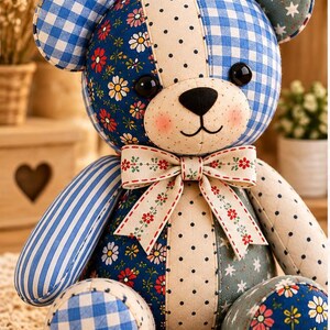 May include: A patchwork teddy bear constructed from various fabric patterns including blue gingham, floral prints, polka dots, and star motifs. The bear features black button eyes, a stitched nose and mouth, pink cheeks, and a decorative bow at the neck.