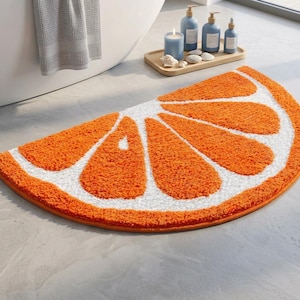 Può includere: Un tappetino da bagno semicircolare con un motivo a fetta di agrume arancione e bianco. Il tappeto presenta una superficie in fibra testurizzata e morbida che ricorda gli spicchi di un'arancia, con sezioni arancioni vivaci separate da bordi bianchi.