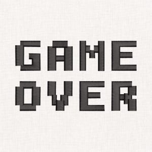 Può includere: Un disegno ricamato in nero con le parole GAME OVER in un carattere a blocchi in stile pixel. Le lettere sono cucite con una trama di filo visibile, creando un aspetto strutturato su uno sfondo di tessuto chiaro e uniforme.