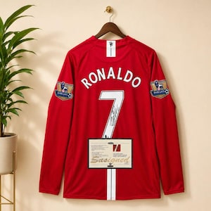 May include: A red long-sleeve sports jersey featuring the name RONALDO and the number 7 in white on the back. The jersey includes Barclays Premier League patches on both sleeves and a rectangular certificate of authenticity label.