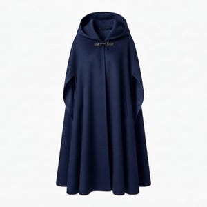 May include: A solid navy blue hooded cape featuring a structured silhouette with an open front design. The garment is secured at the neckline with a single dark brown leather toggle closure, creating a clean and uniform appearance throughout.