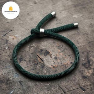 Puede incluir: Una pulsera de cordón verde oscuro con un mecanismo de nudo deslizante para su ajuste. La pulsera está fabricada con un material de cuerda trenzada gruesa y cuenta con dos terminales metálicos de color plateado pulido en los extremos.