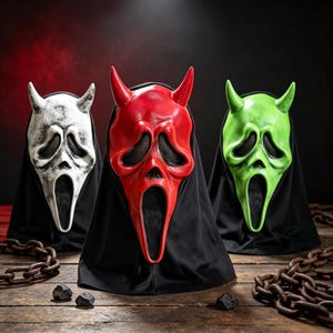 May include: Three devil-themed masks with elongated faces, hollow eye sockets with black mesh, and open mouths. The masks are white with black weathering, solid red, and bright green, each featuring two horns and an attached black fabric hood.