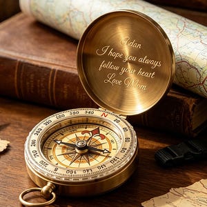 Peut inclure: Une boussole de poche en laiton avec un couvercle à charnière portant l'inscription gravée : Adan, I hope you always follow your heart, Love Mom. La boussole présente un cadran circulaire avec les points cardinaux et des degrés.