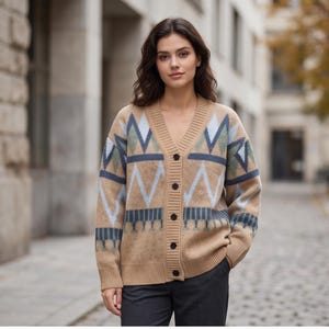 May include: A tan V-neck cardigan sweater featuring a geometric pattern in shades of light blue, dark blue, and muted green. The knit garment has a button-down front with five dark buttons, long sleeves, and ribbed cuffs and hemline details.