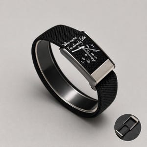 May include: A black fabric watch band featuring a silver-toned metal clasp and a rectangular face plate printed with a clock dial and the text "Who cares I'm already late". The watch band has a textured weave and includes a separate metal connector.