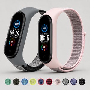 May include: Two fitness trackers with black digital screens displaying 08:16, 8000 steps, and 80 heart rate. One tracker has a solid gray silicone frame with a gray woven strap, and the other has a pale pink silicone frame with a pink woven strap.