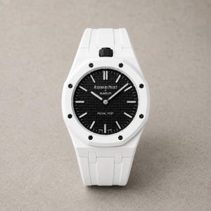 Puede incluir: Un reloj de pulsera blanco con una esfera negra texturizada que presenta el texto Audemars Piguet x Swatch y Royal Pop. El reloj tiene un bisel blanco con ocho tornillos hexagonales negros, marcadores de hora plateados, manecillas plateadas y una corona negra.