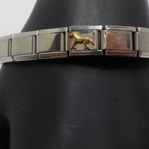 May include: A silver charm bracelet with a gold horse charm. The bracelet is made of interlocking links.