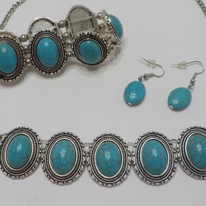 May include: A turquoise and silver jewellery set with a necklace, bracelet, and earrings. The necklace and bracelet feature oval turquoise stones set in silver frames. The earrings are silver with turquoise stones.